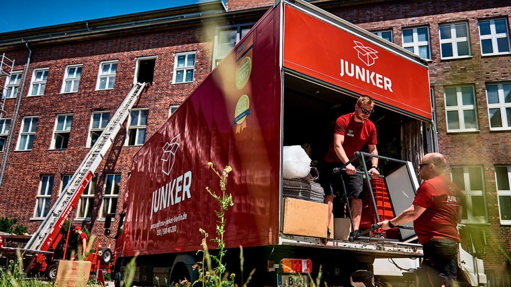 Junker Umzüge Team entlädt Kartons mithilfe eines Umzugslifts vor einem Berliner Gebäude